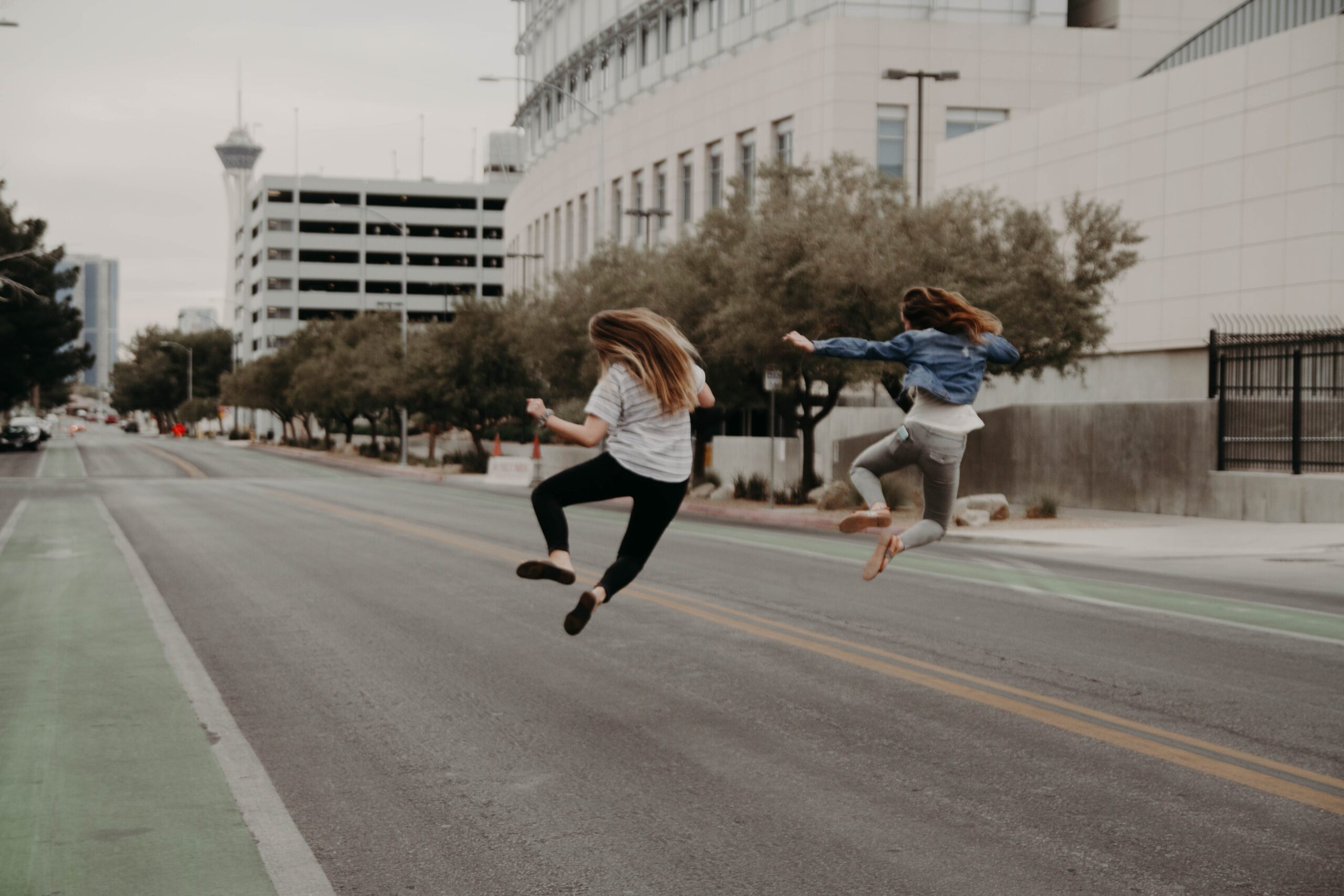 女性二人が道路の真ん中でシンクロしながらジャンプしている